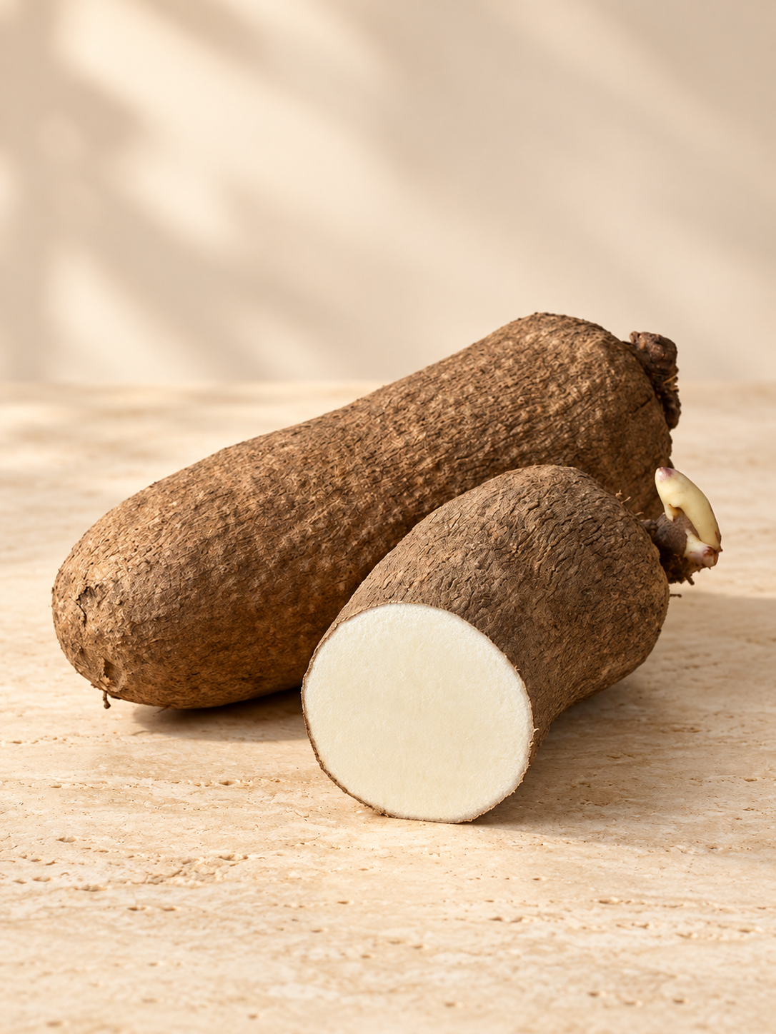 Fresh white yams on a warm cream travertine surface